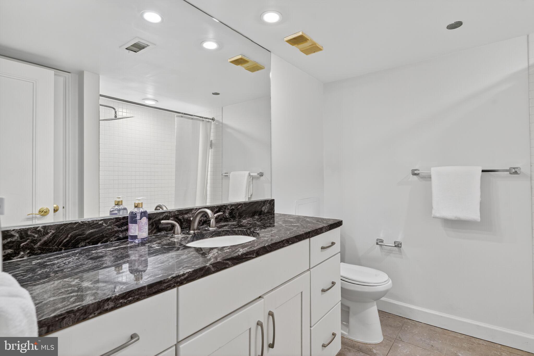 4550 North Park Avenue, Unit 814 Chevy Chase, MD 20815 - Photo 13 of 25 a bathroom with a granite countertop sink a toilet and a mirror