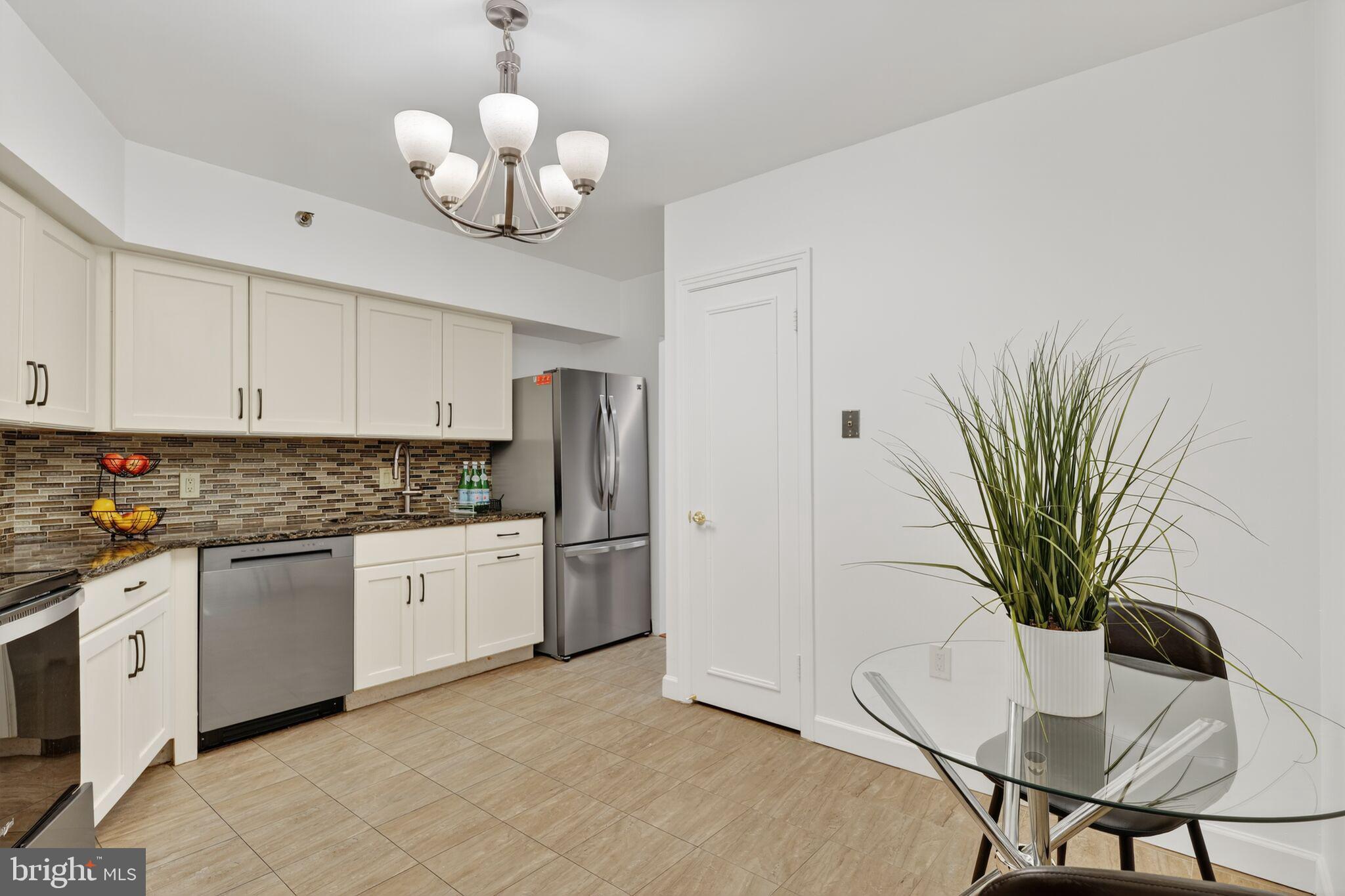 4550 North Park Avenue, Unit 814 Chevy Chase, MD 20815 - Photo 8 of 25 a kitchen with stainless steel appliances granite countertop a refrigerator a stove a sink dishwasher and white cabinets with wooden floor