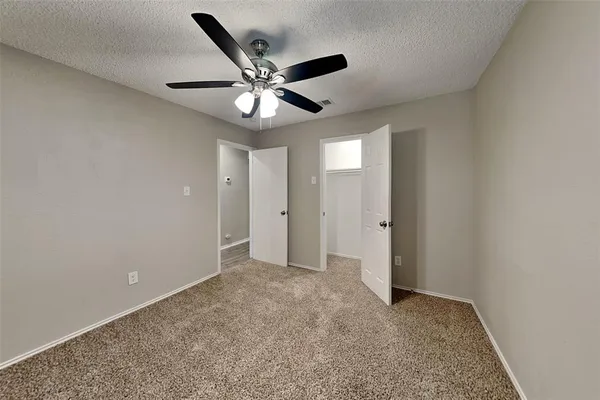 an empty room with closet and a chandelier fan