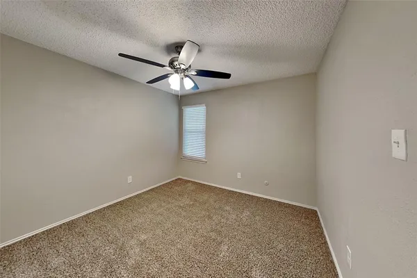 an empty room with a window and a ceiling fan