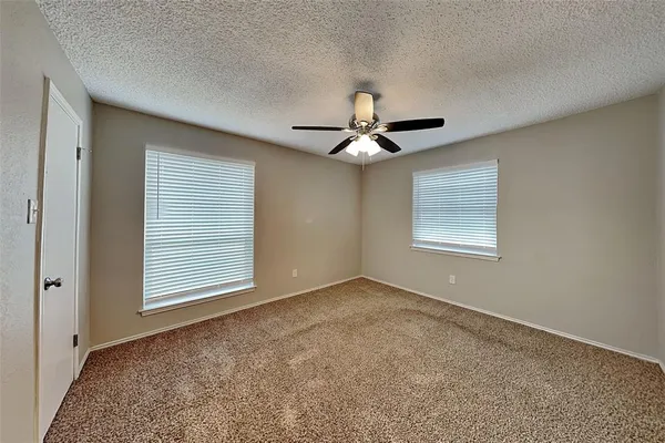 an empty room with windows and fan