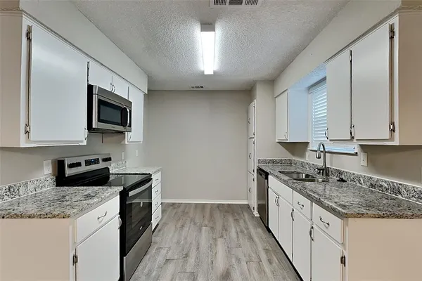 a kitchen with granite countertop stainless steel appliances a stove sink microwave and cabinets