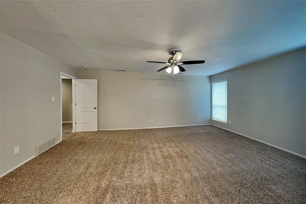 a view of an empty room with a chandelier fan