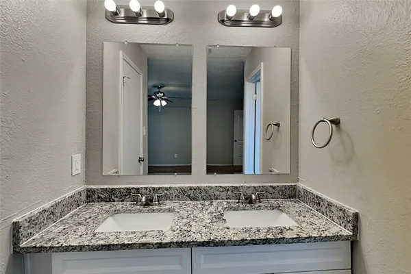 a bathroom with a granite countertop sink and a mirror