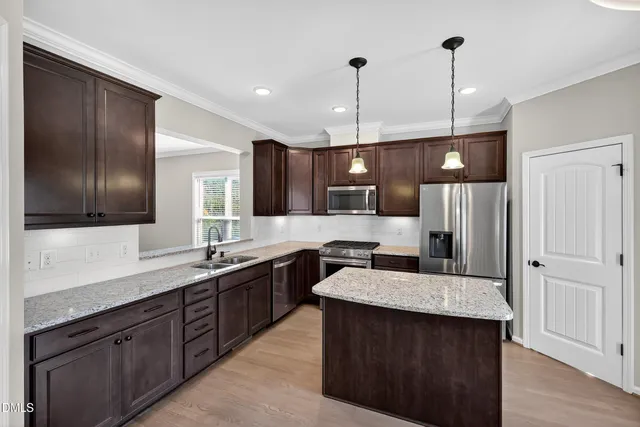 a large kitchen with a center island wooden floor and stainless steel appliances