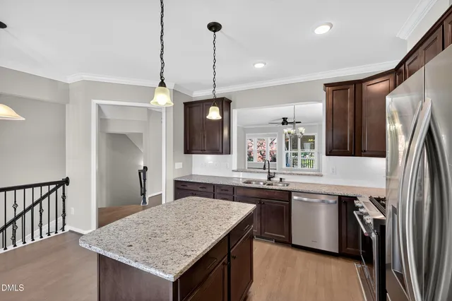 a kitchen with stainless steel appliances granite countertop a sink a stove a refrigerator and island