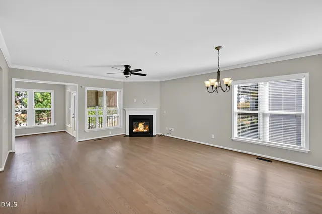 an empty room with wooden floor fireplace and windows