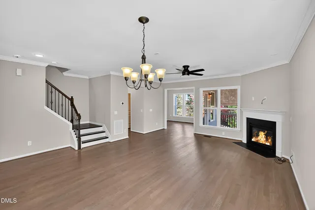 a view of an empty room with wooden floor fireplace and a window