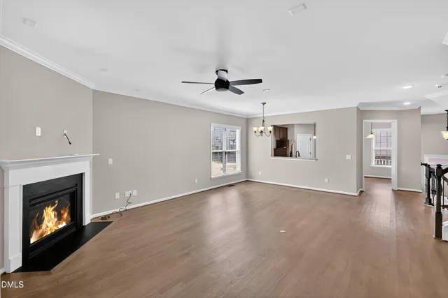 a view of an empty room with wooden floor fireplace and a window