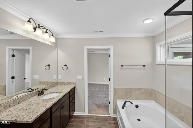 a bathroom with a sink double vanity granite tub shower and a mirror