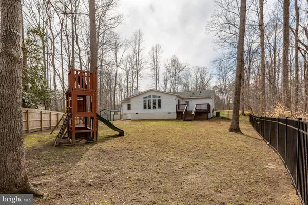 a backyard of a house with large trees and barbeque oven