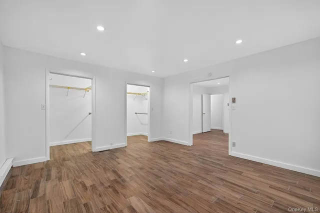 a view of an empty room with wooden floor and closet