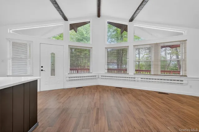a view of an empty room with wooden floor and a window