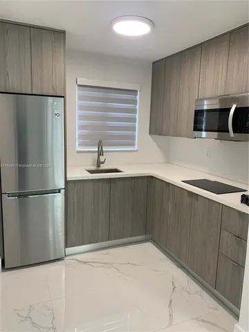 a kitchen with granite countertop a refrigerator and a sink