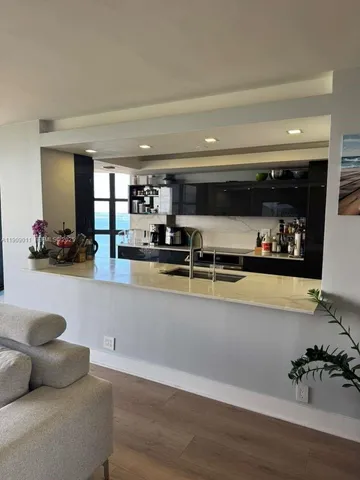 a living room with stainless steel appliances kitchen island granite countertop a couch and a counter space