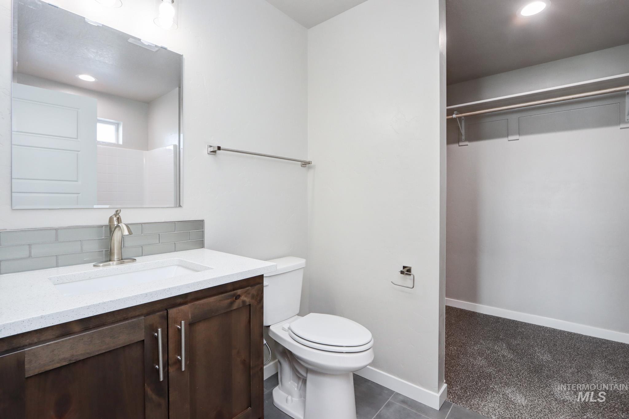 824 North 5th Street Nyssa, OR 97913 - Photo 11 of 23 Bathroom with a walk in closet, vanity, recessed lighting, dark tile patterned floors, and dark colored carpet