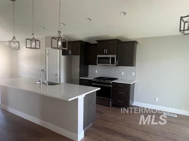 824 North 5th Street Nyssa, OR 97913 - Photo 2 of 23 Kitchen with hanging light fixtures, stainless steel appliances, decorative backsplash, a kitchen island with sink, and recessed lighting