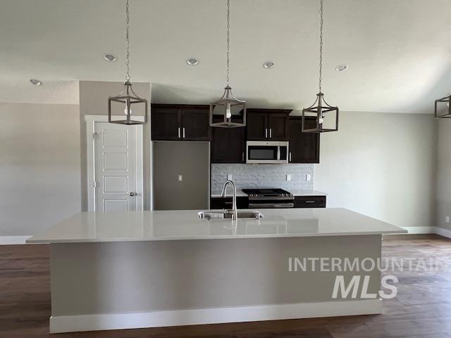 824 North 5th Street Nyssa, OR 97913 - Photo 3 of 23 Kitchen featuring decorative light fixtures, appliances with stainless steel finishes, a center island with sink, tasteful backsplash, and light stone counters