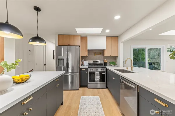 a kitchen with stainless steel appliances granite countertop a sink a stove and refrigerator