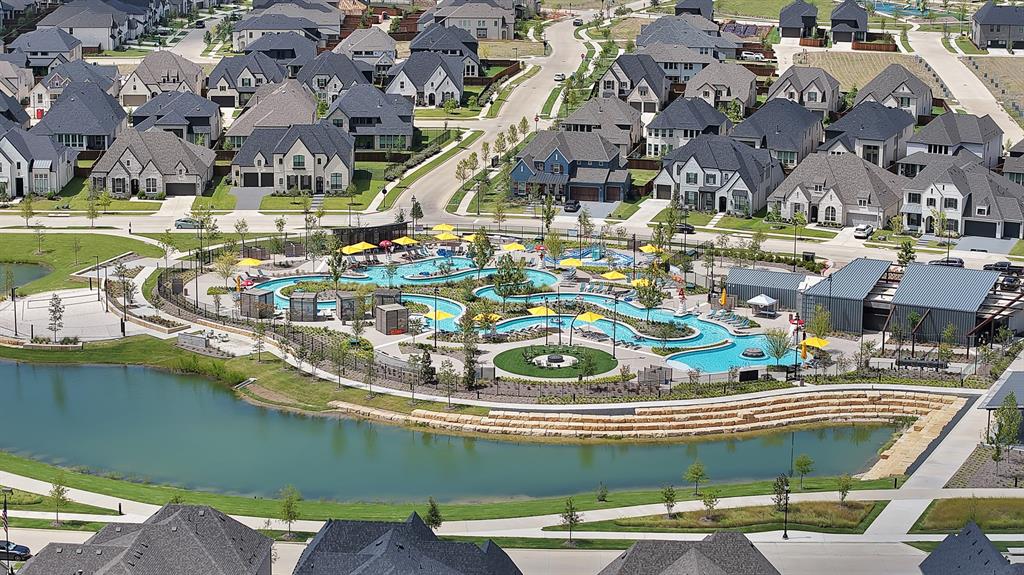 5012 Triadic Lane Prosper, TX 75078 - Photo 37 of 38 Expansive community featuring numerous residential properties with diverse architectural styles, a central water park with multiple pools and slides, a tranquil pond, and extensive manicured green spaces