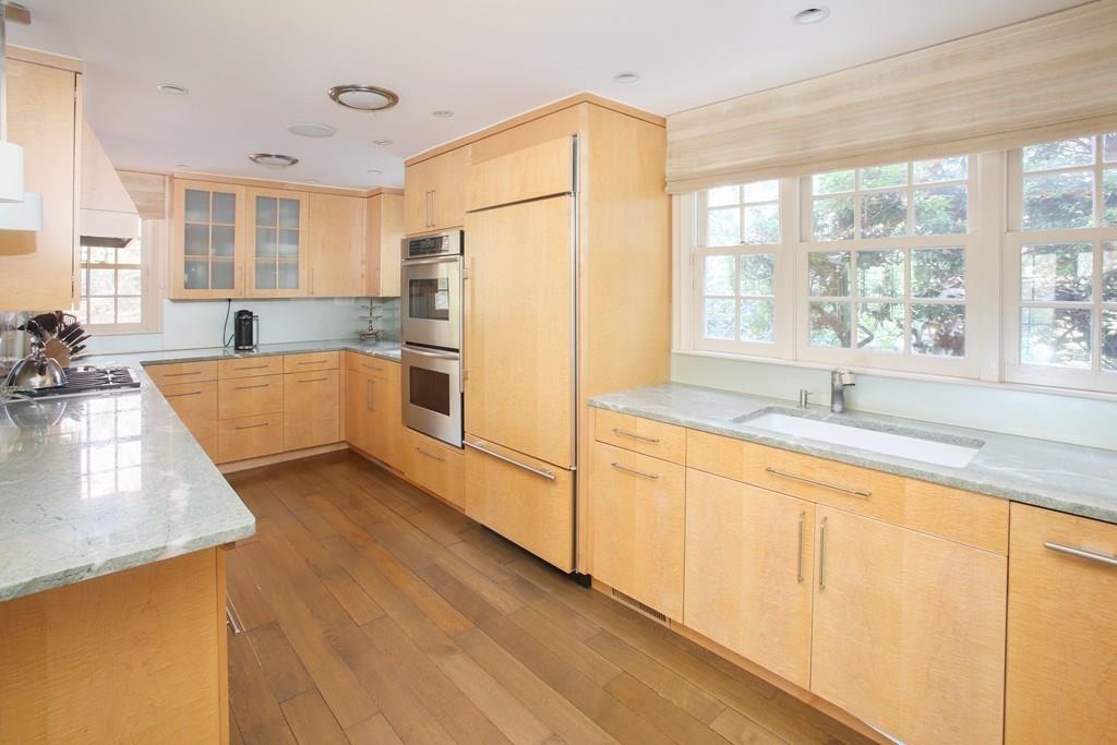 97 Laurel Road Brookline, MA 02467 - Photo 7 of 33 a large kitchen with stainless steel appliances granite countertop a refrigerator a sink dishwasher a stove and white countertops with wooden floor