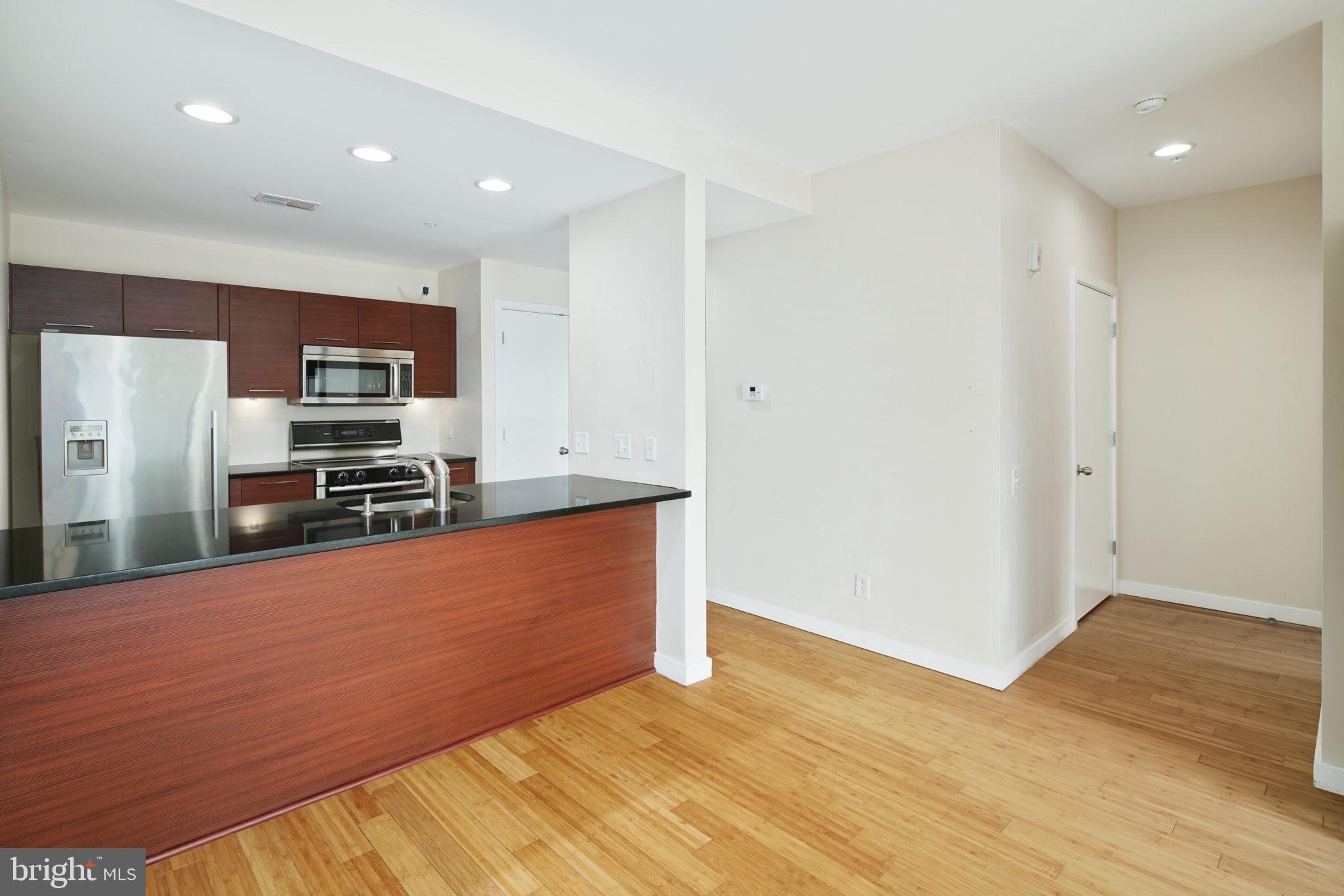 a large kitchen with stainless steel appliances wooden floor and a refrigerator