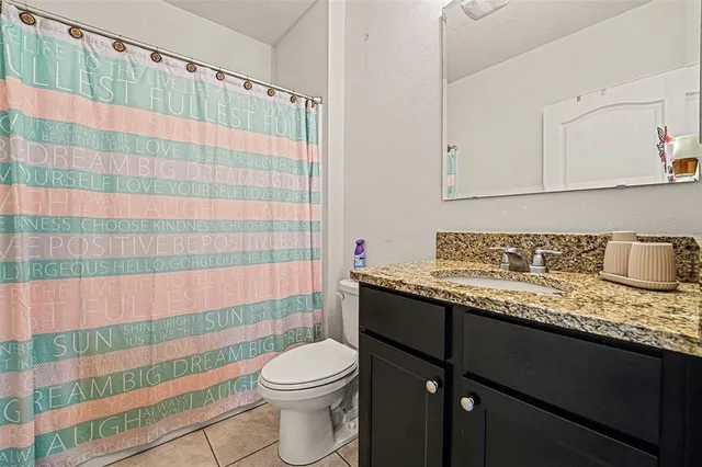 a bathroom with a granite countertop sink a toilet and shower