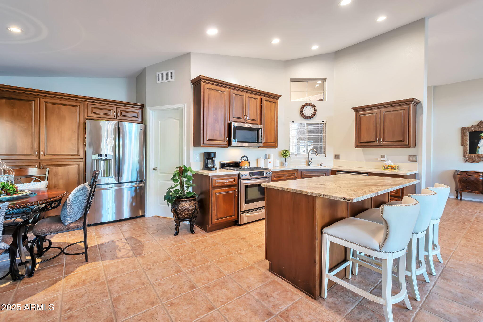 15460 West Merrell Street Goodyear, AZ 85395 - Photo 13 of 30 a kitchen with a refrigerator a stove top oven a sink dishwasher and chairs with wooden cabinets