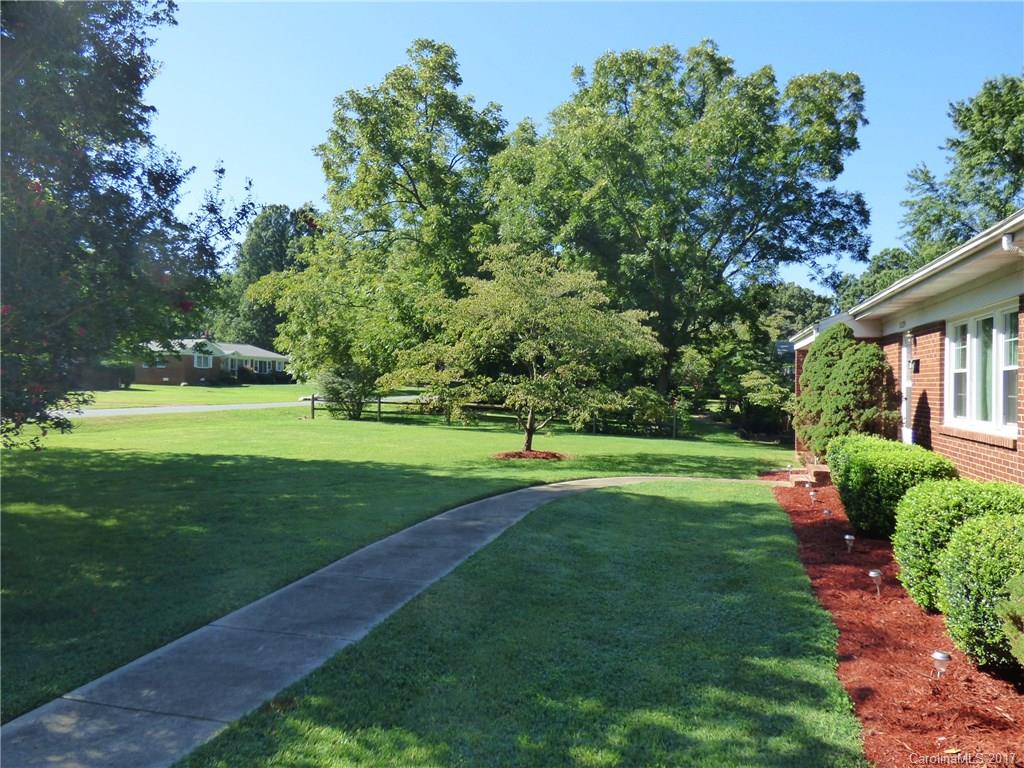 5229 Manning Road Charlotte, NC 28269 - Photo 4 of 18 a view of a white house in front of a big yard with plants and large trees