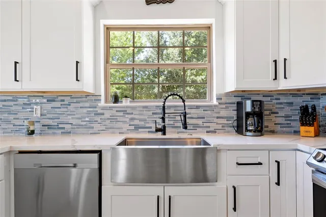 a kitchen with stainless steel appliances granite countertop white cabinets sink a stove and a microwave