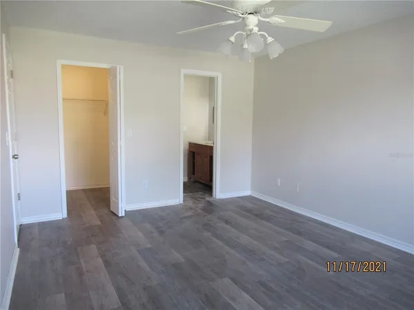 an empty room with wooden floor closet and windows