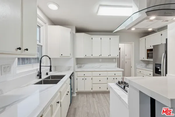 a kitchen with a sink white cabinets and stainless steel appliances