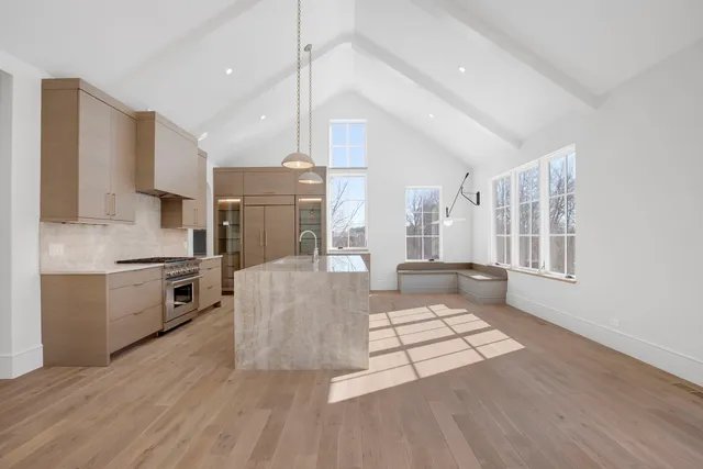 a large kitchen with stainless steel appliances a large counter top a stove a chimney a sink and a refrigerator