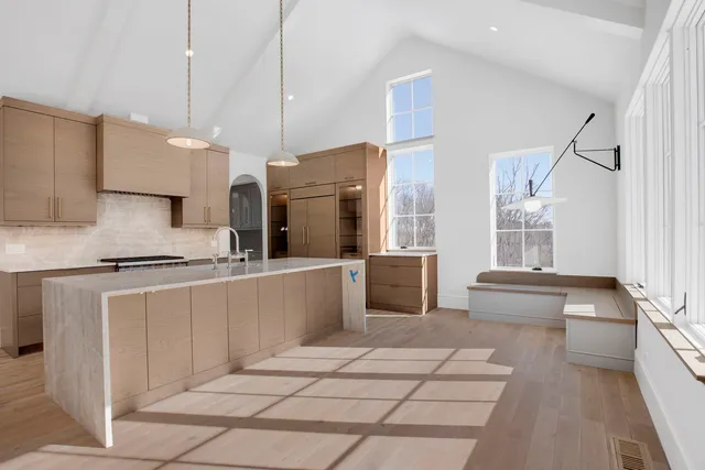 a large kitchen with kitchen island a large counter top stainless steel appliances and cabinets