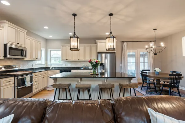 a kitchen with stainless steel appliances granite countertop a stove top oven a sink a dining table and chairs