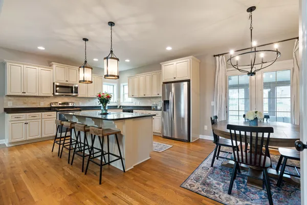 a kitchen with stainless steel appliances granite countertop a stove a refrigerator a kitchen island a dining table and chairs