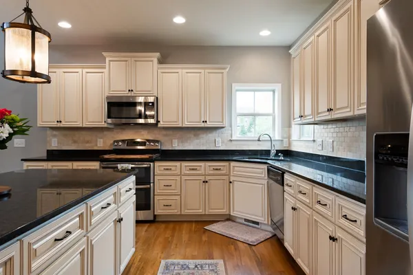 a kitchen with stainless steel appliances granite countertop a sink a stove a refrigerator and cabinets