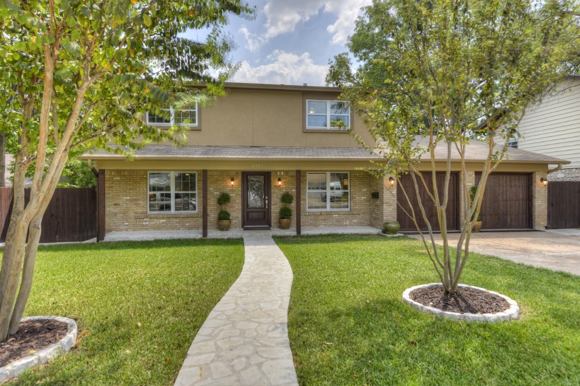 a front view of a house with a yard and trees