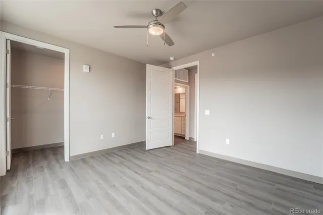 a view of an empty room and wooden floor ceiling fan