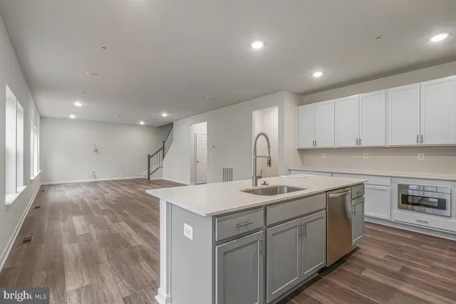 a kitchen with a sink a stove a refrigerator and white cabinets with wooden floor