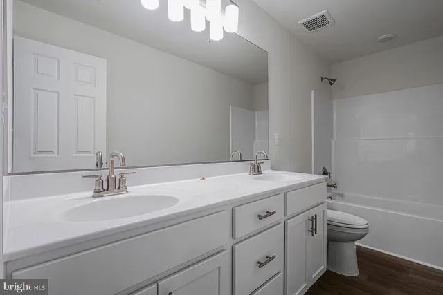 a bathroom with a granite countertop toilet a sink and mirror