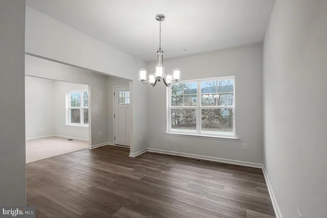an empty room with wooden floor chandelier and windows