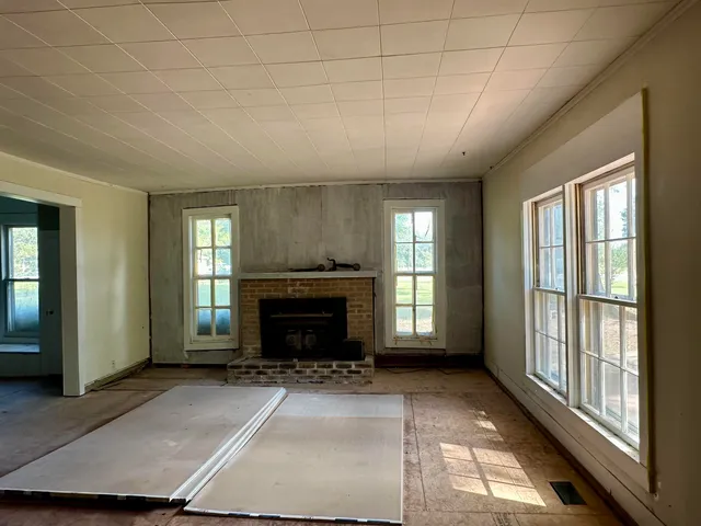 an empty room with windows and fireplace