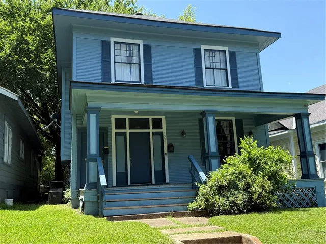a view of a house with potted plants and a large tree