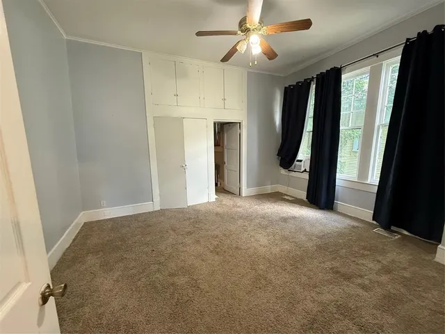 an empty room with a window and a ceiling fan