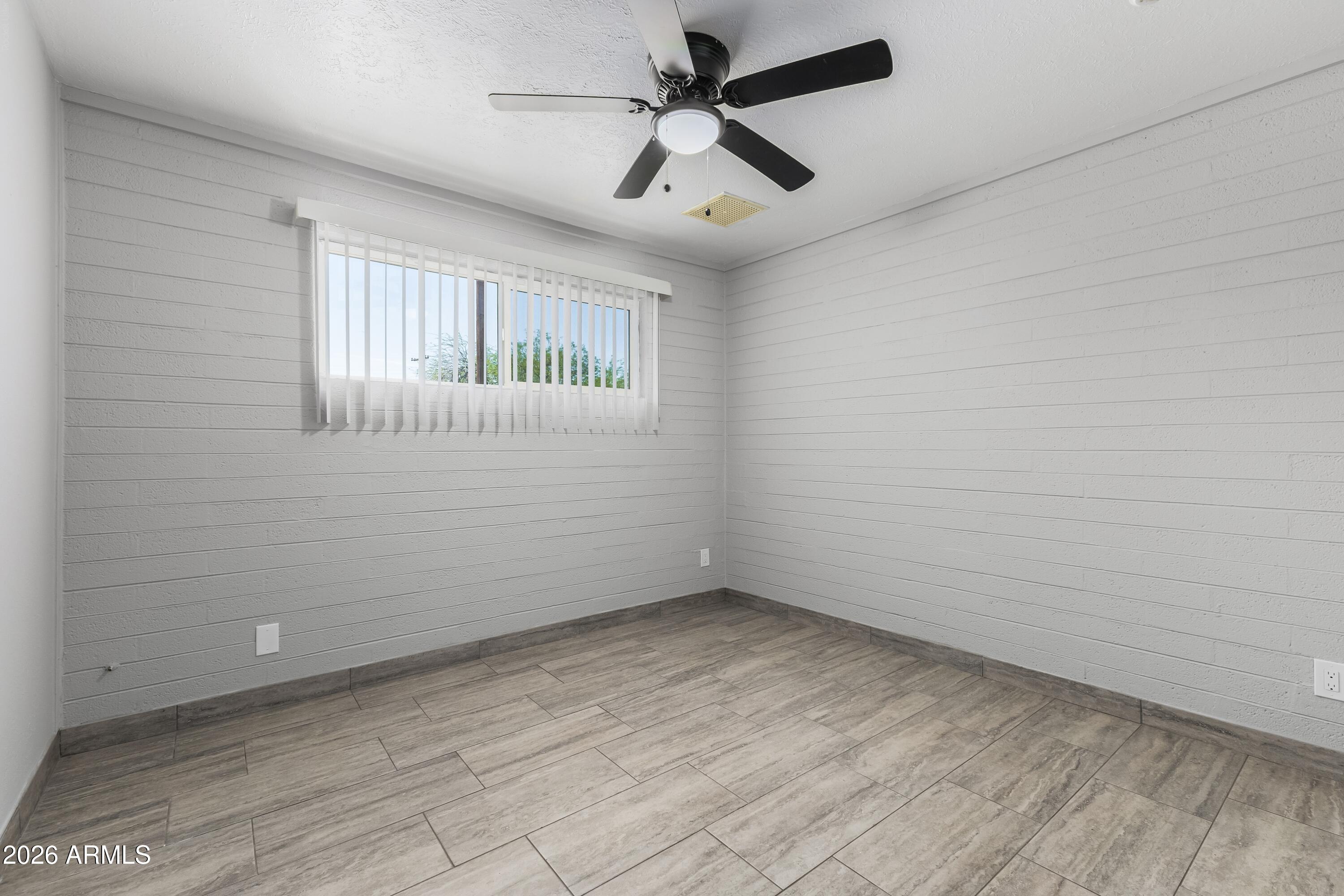 3137 North 37th Drive Phoenix, AZ 85019 - Photo 12 of 18 an empty room with a window and ceiling fan