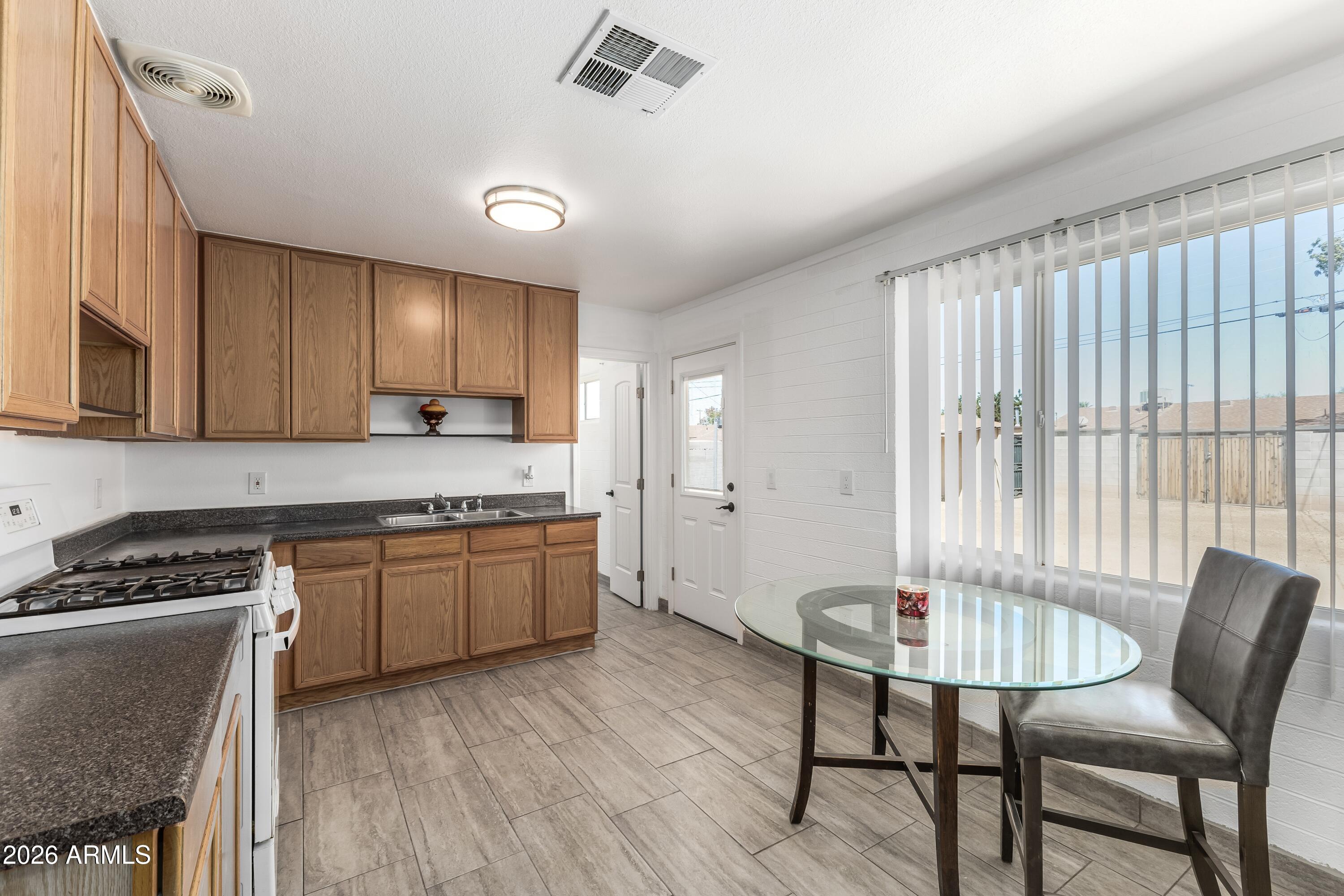 3137 North 37th Drive Phoenix, AZ 85019 - Photo 3 of 18 a kitchen with granite countertop a stove a sink cabinets and a wooden floor