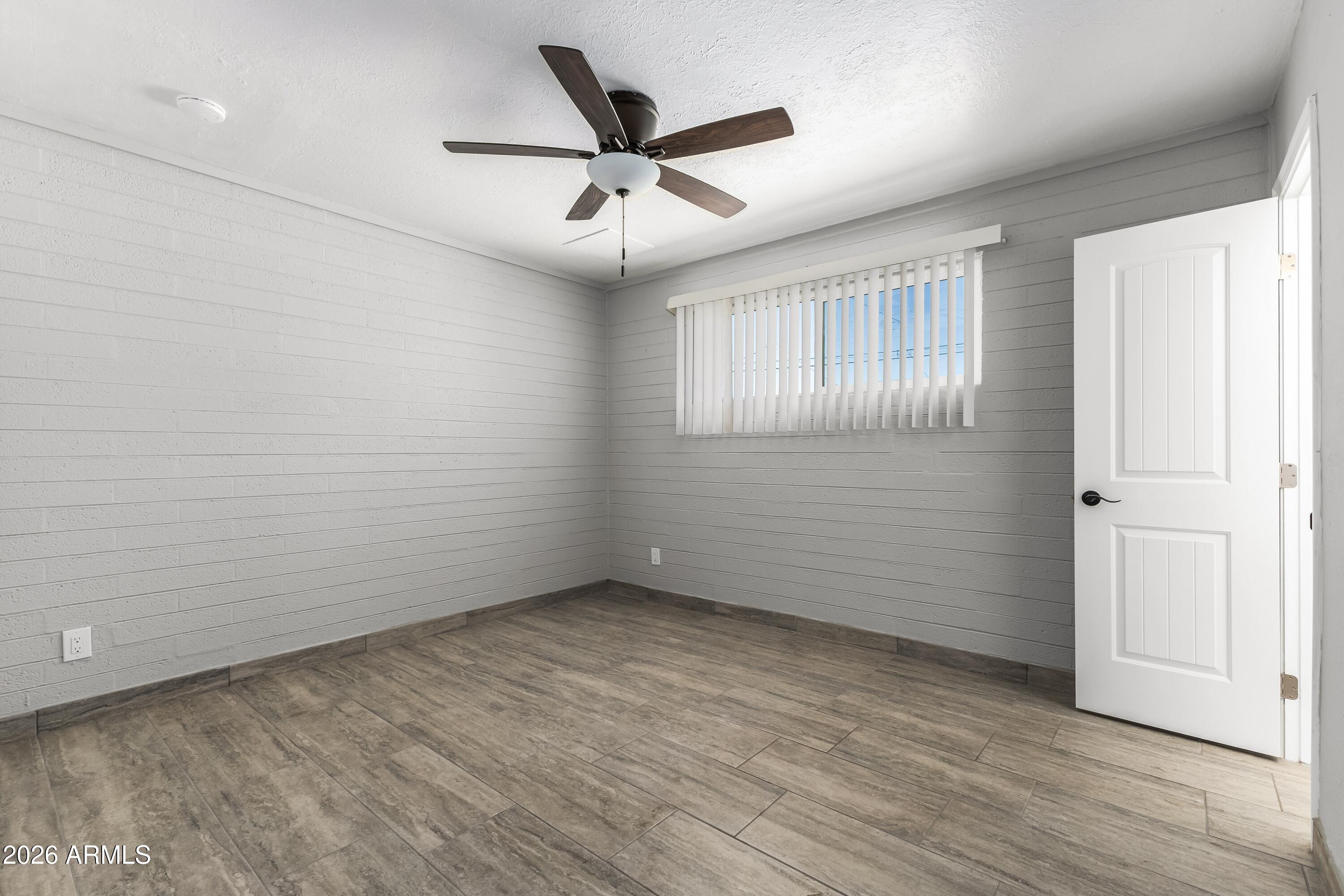 3137 North 37th Drive Phoenix, AZ 85019 - Photo 5 of 18 an empty room with wooden floor ceiling fan and windows