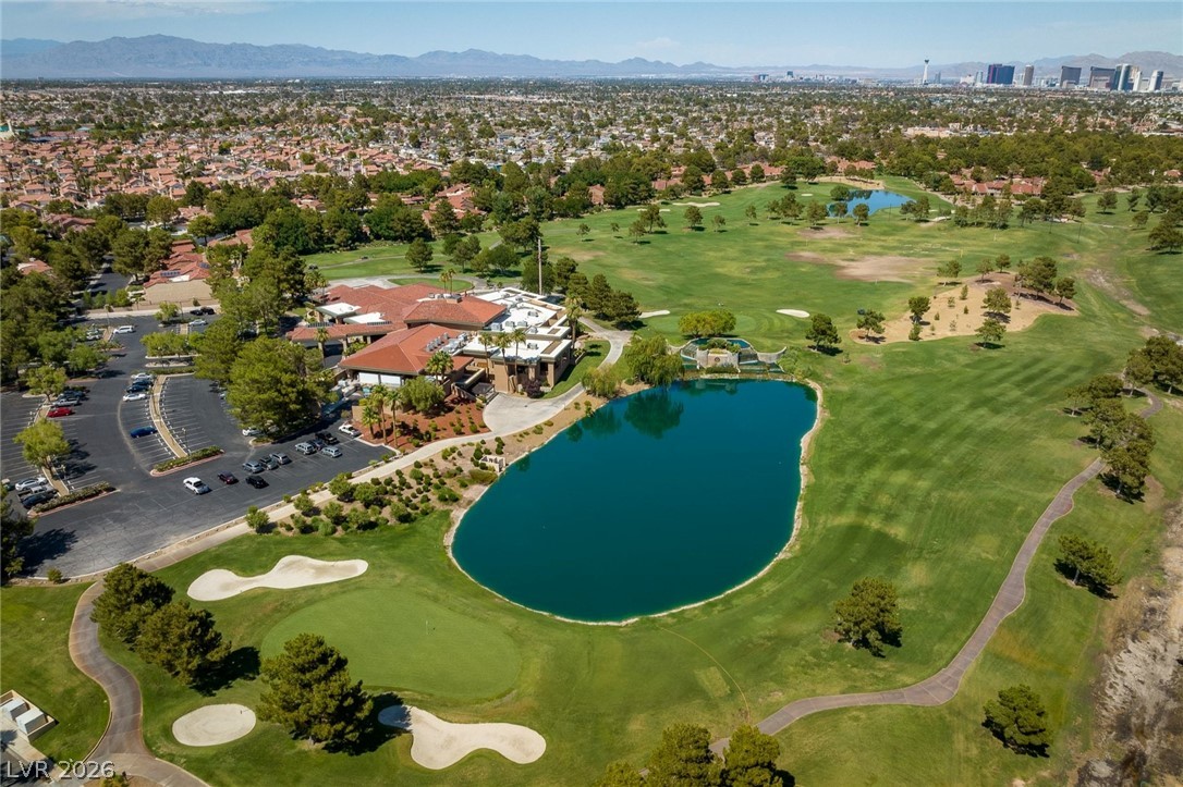 20 Innisbrook Avenue Las Vegas, NV 89113 - Photo 23 of 39 An aerial perspective reveals a vibrant golf course with a serene lake, framed by residential neighborhoods and distant mountains.