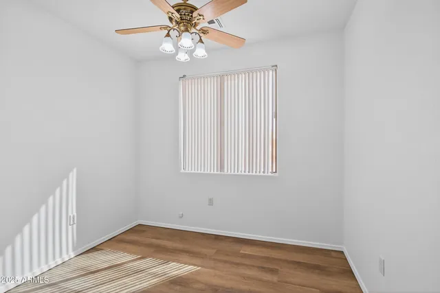 an empty room with wooden floor fan and windows